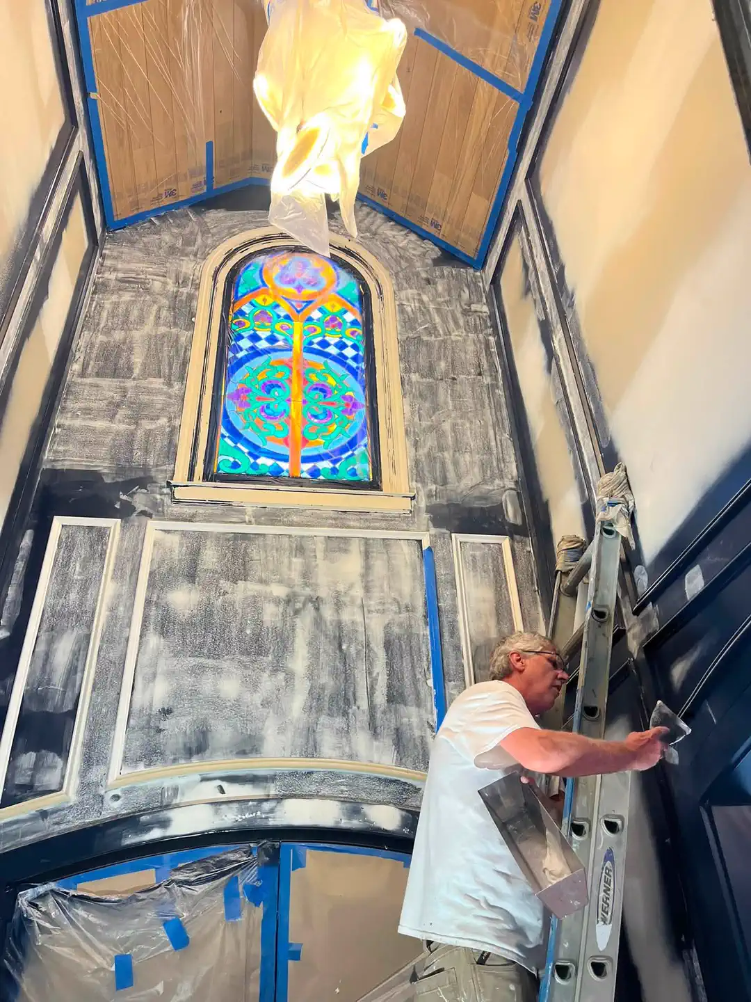 Painter applying a layered decorative wall finish in the tall foyer