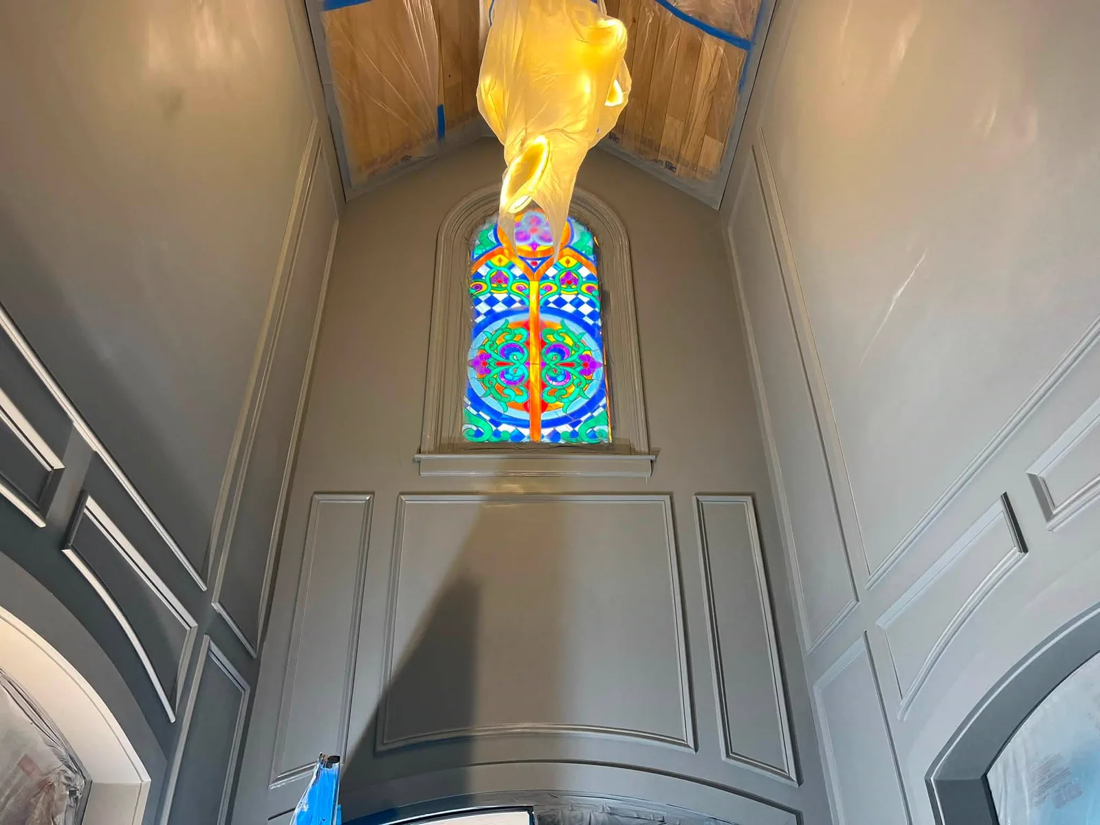 Finished decorative foyer with paneled gray walls and a stained-glass window