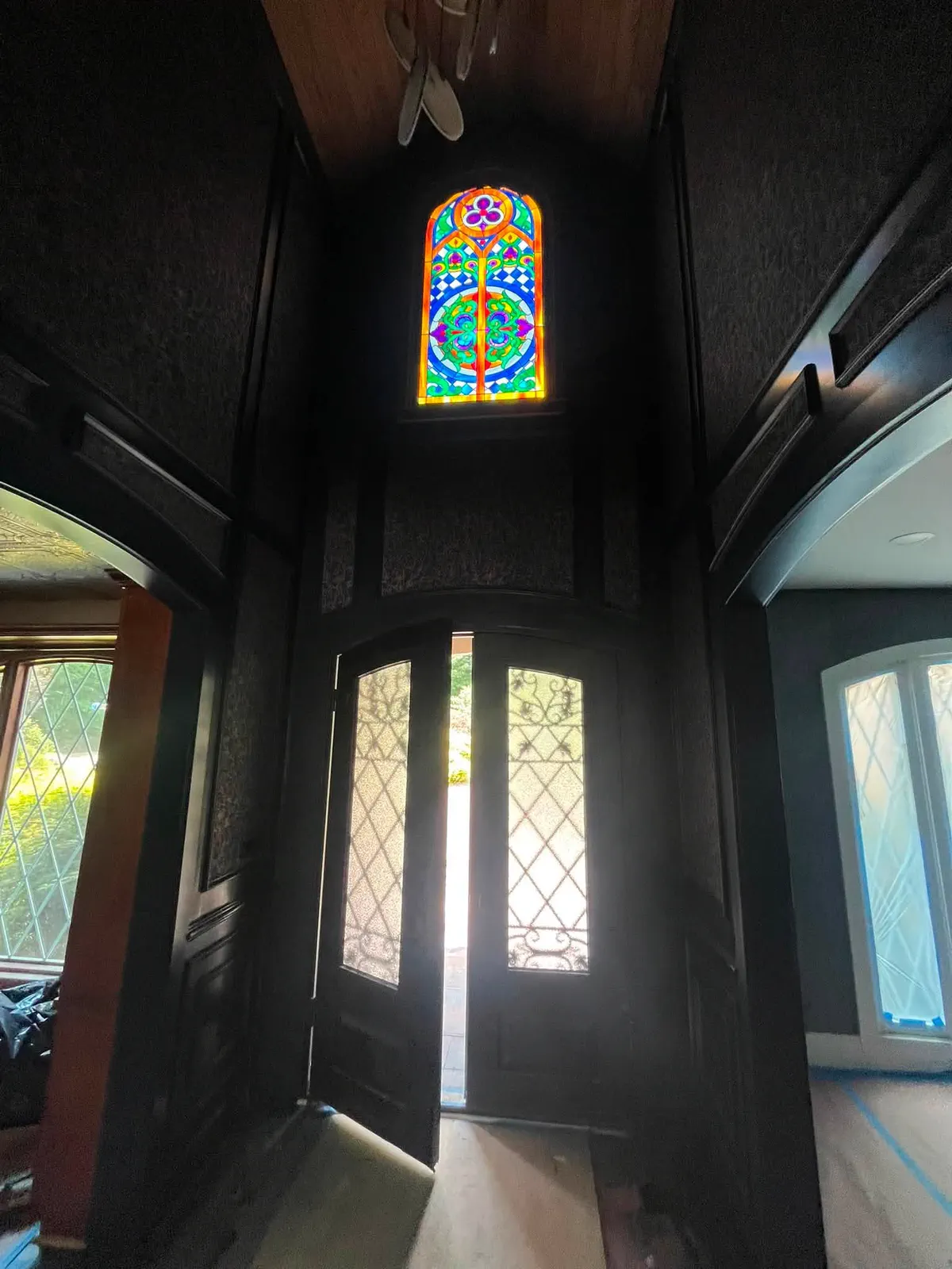 Finished dark foyer walls framing the stained-glass entry