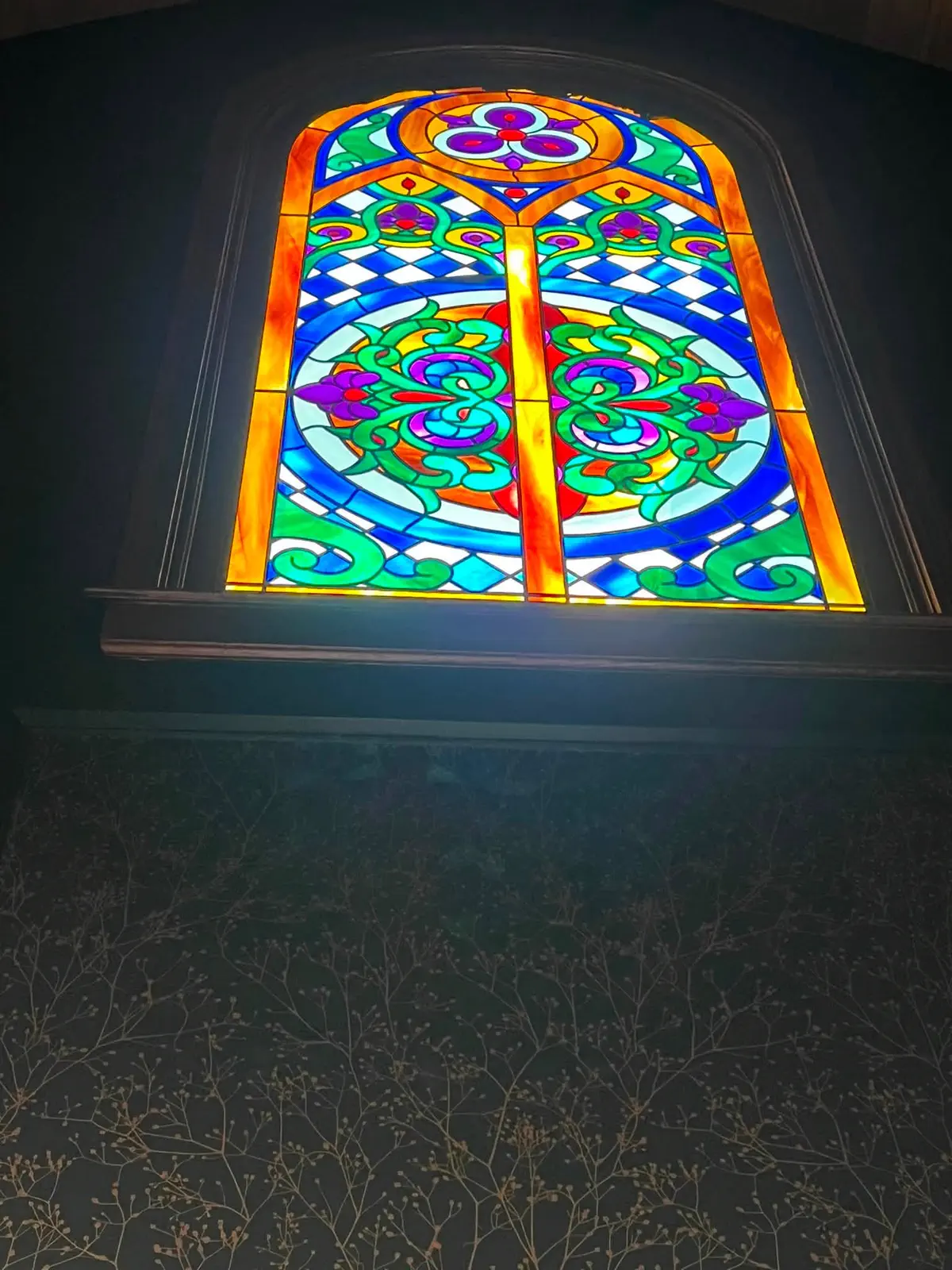 Stained-glass window framed by the completed decorative wall finish
