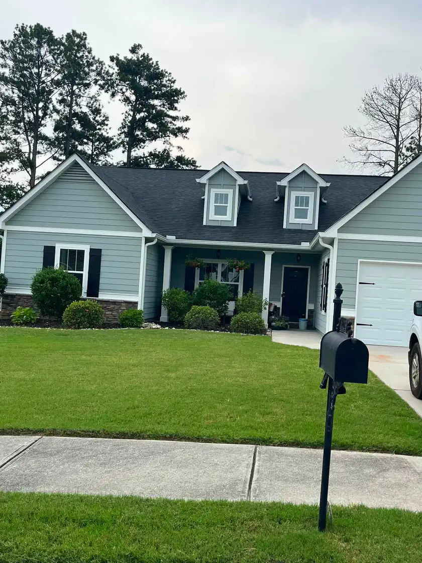 Completed blue-gray exterior painting viewed from across the front lawn