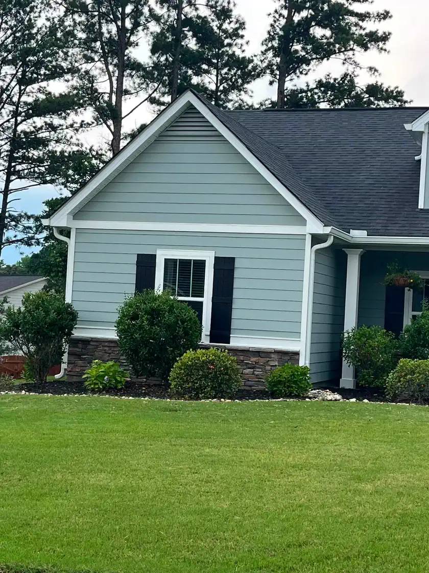 Finished blue-gray home exterior with crisp white trim and a landscaped front lawn
