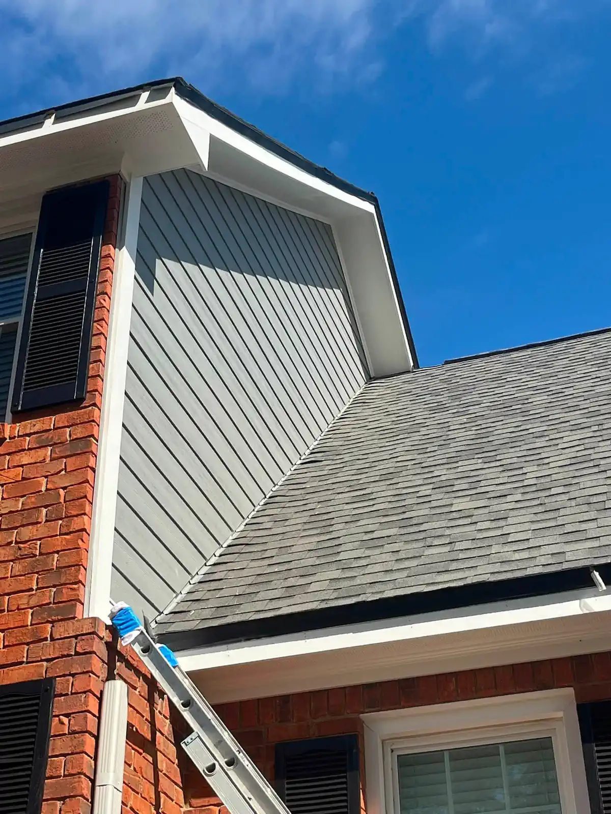 Blue-gray paint being applied to the upper gable siding