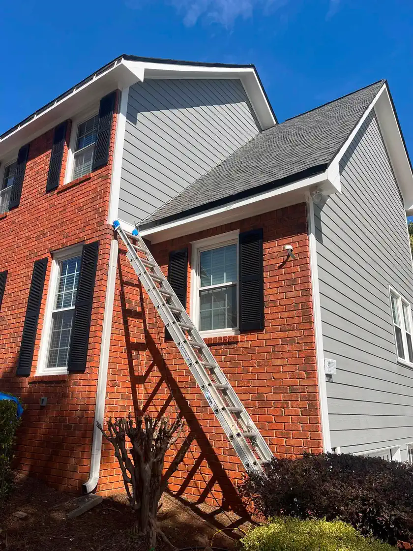 Upper siding being repainted blue-gray above the red brick facade
