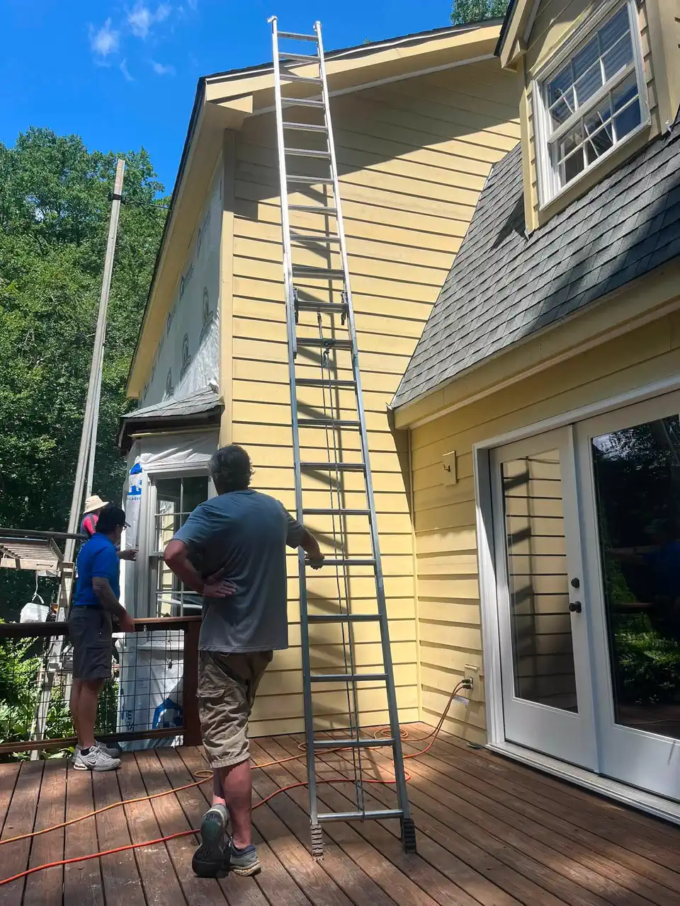 Painting crew working from ladders on the two-story exterior